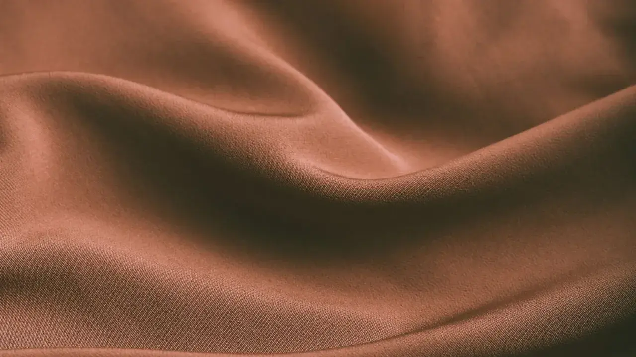 Brązowa, pofałdowana tkanina. Czy spandex oddycha? Ta gładka powierzchnia sugeruje komfort i lekkość.