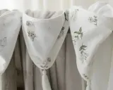 Trzy białe kocyki z motywami zwierząt i kwiatów, wykonane z delikatnego materiału, podobnego do batystu, z ozdobnymi chwostami.
