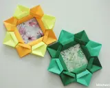 Dwa ozdobne ramki na zdjęcia diy w kształcie gwiazdy, wykonane z kolorowego papieru origami. Jedna żółto-pomarańczowa, druga zielona.