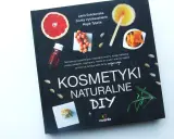 Okładka książki "Kosmetyki Naturalne DIY" z pomarańczą, owocami rokitnika, migdałami i ziołami.