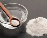 Soda oczyszczona na łyżce i obok kupka proszku. To składniki, które pomogą Ci dowiedzieć się, jak zmiękczyć len.