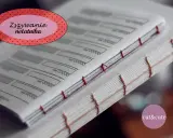 Ręczne szycie książki, czyli notatnika. Widać czerwone nici łączące strony, tworząc estetyczne grzbiety.