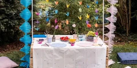 Kolorowe żurawie origami i girlandy tworzą magiczne ozdoby na stół zrób to sam. Urocza aranżacja w ogrodzie.