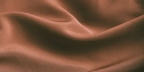 Brązowa, pofałdowana tkanina. Czy spandex oddycha? Ta gładka powierzchnia sugeruje komfort i lekkość.