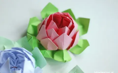 Różowy i niebieski kwiat origami prosty, otoczony zielonymi listkami.