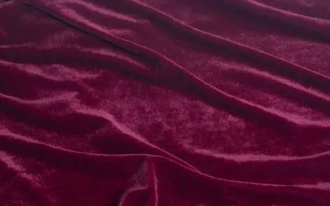 Głęboki, burgundowy welur układa się w miękkie fale, przypominając aksamitny dywan.