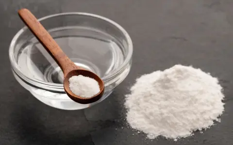 Soda oczyszczona na łyżce i obok kupka proszku. To składniki, które pomogą Ci dowiedzieć się, jak zmiękczyć len.