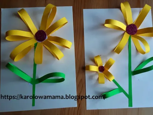 Proste kwiaty z papieru dla dzieci. Dwa żółte słoneczniki z zielonymi łodygami i liśćmi, wykonane z papieru.