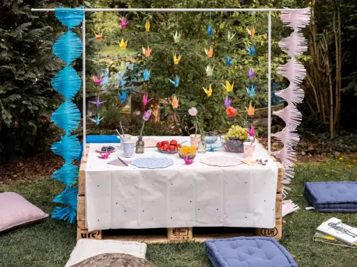Kolorowe żurawie origami i girlandy tworzą magiczne ozdoby na stół zrób to sam. Urocza aranżacja w ogrodzie.