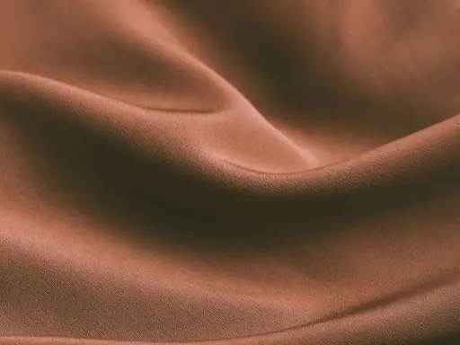 Brązowa, pofałdowana tkanina. Czy spandex oddycha? Ta gładka powierzchnia sugeruje komfort i lekkość.