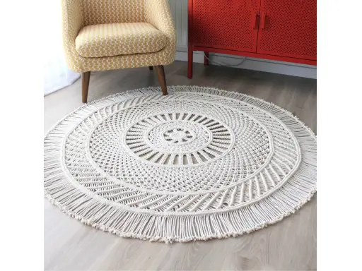 Okrągły dywan makrama w kolorze ecru z frędzlami, ozdobiony misternym wzorem. Idealny do salonu.