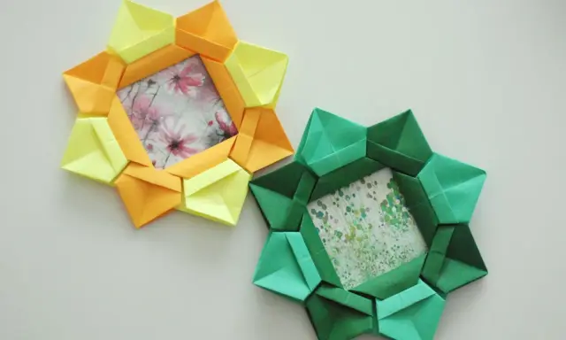 Dwa ozdobne ramki na zdjęcia diy w kształcie gwiazdy, wykonane z kolorowego papieru origami. Jedna żółto-pomarańczowa, druga zielona.