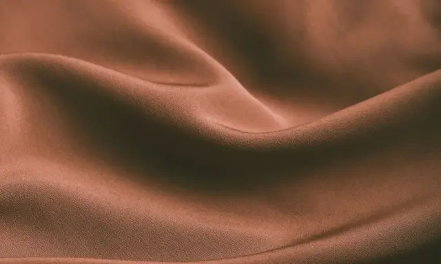 Brązowa, pofałdowana tkanina. Czy spandex oddycha? Ta gładka powierzchnia sugeruje komfort i lekkość.